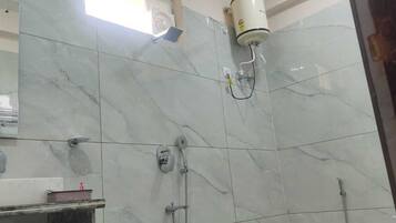 Un baño con azulejos de mármol, un secador de manos, un perchero para toallas y un cabezal de ducha.