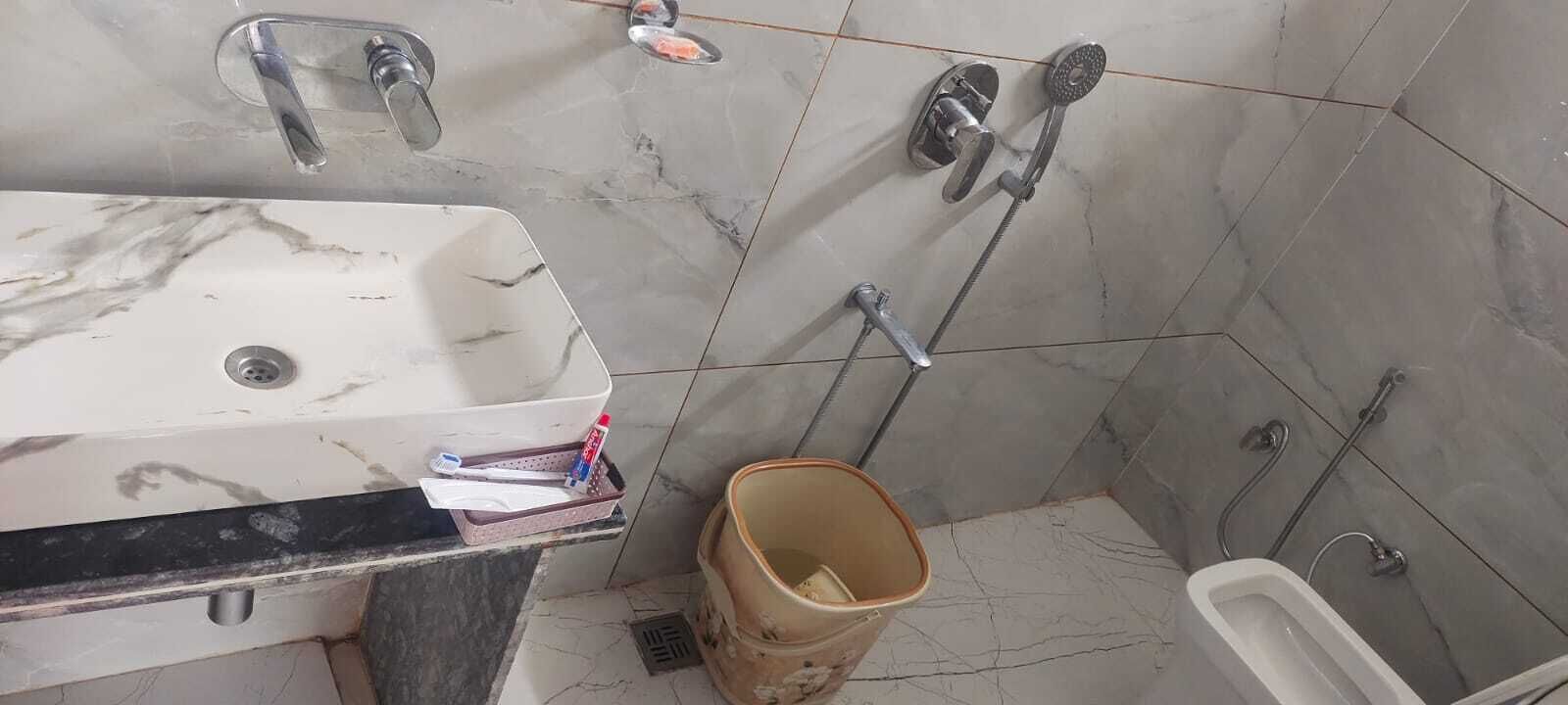 Un baño con lavamanos, dos cabezales de ducha y un inodoro.