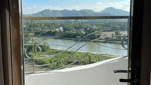 A view from a balcony with a metal railing, overlooking a river, greenery, and distant mountains. - Rex Hotel Binh Dinh - by BAY LUXURY (Binh Dinh)