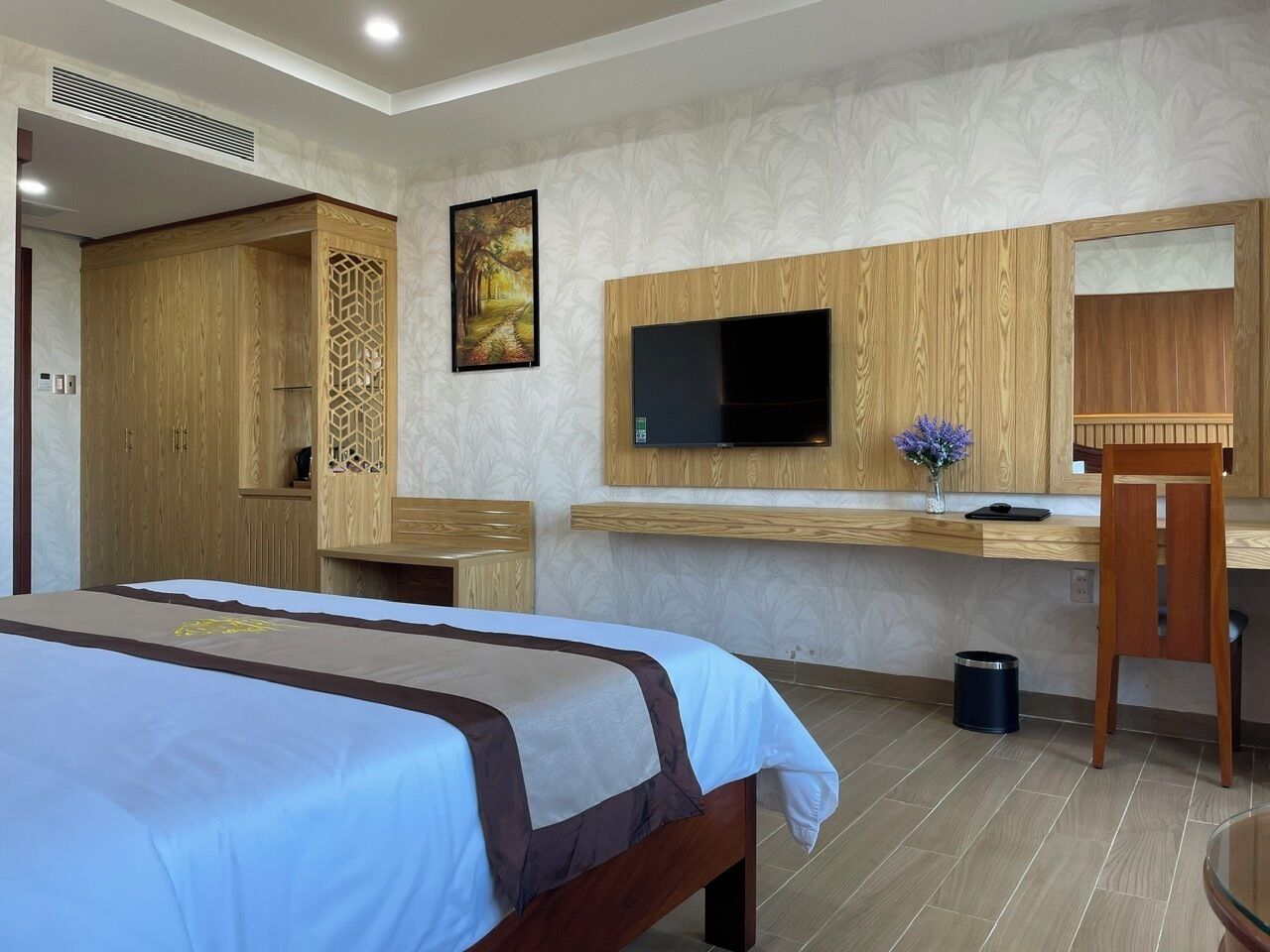 Habitación de hotel con dos camas, un televisor montado en la pared, un escritorio con una silla y un armario de madera.