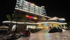 A modern hotel with a curved facade, multiple balconies, and a well-lit entrance. - Rex Hotel Binh Dinh - by BAY LUXURY (Binh Dinh)