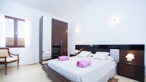 A modern hotel room with a large bed, a wooden chair, a wardrobe, and a nightstand with a lamp. - Can Melis - Villa With Private Pool In Campanet (Campanet, Illes Balears)