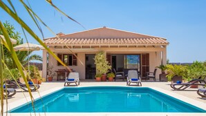 A poolside area with a clear blue pool, lounge chairs, and potted plants. - Can Melis - Villa With Private Pool In Campanet (Campanet, Illes Balears)