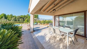 Un patio moderno al aire libre con mesa y sillas, piscina y vistas a las montañas.