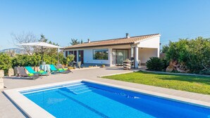 Una casa moderna con piscina, mobiliario exterior y un jardín cuidado.