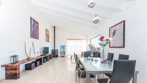 Un comedor amplio con un largo banco de madera, una mesa de vidrio y sillas negras.