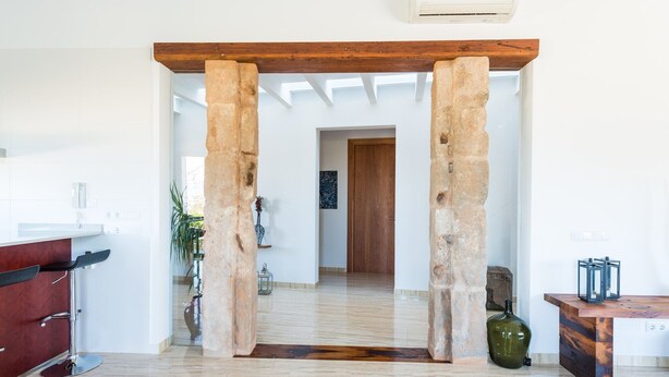 Una cocina moderna con barra, un arco de piedra y techo de madera.
