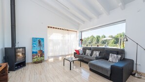 Una sala de estar moderna con chimenea, un sofá, una mesita de centro y un ventanal que ofrece vistas a zonas verdes.