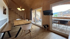 Un interior de madera con comedor, una escalera y un televisor montado en la pared.