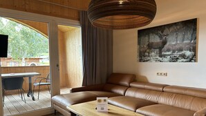 Una sala de estar moderna con un sofá de cuero marrón, una mesa de centro de madera y un cuadro de un ciervo en la pared.