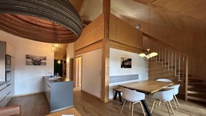 Un interior moderno con una zona de comedor de madera, una cocina y una escalera.