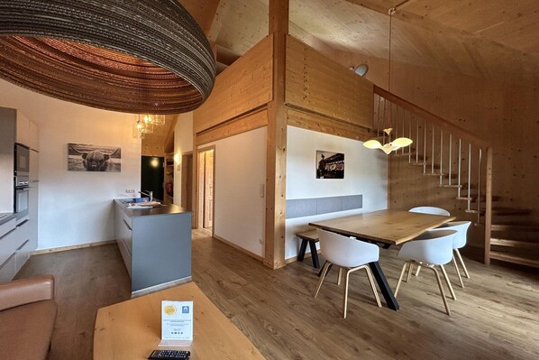 A modern interior with a wooden dining area, a kitchen, and a staircase.