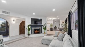 A modern living room with a fireplace, comfortable seating, and a large TV.