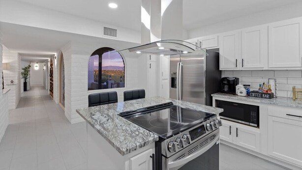 Une cuisine moderne avec des meubles blancs, une cuisinière encastrée et un coin café.