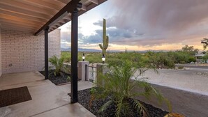 Une terrasse couverte offrant une vue sur un paysage désertique, avec notamment un cactus et des montagnes à l’horizon.