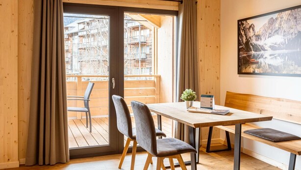 A wooden interior with a balcony, a table with chairs, and a bench.