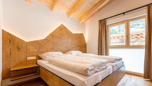 Una camera da letto moderna con una testiera in legno, un letto grande, un comodino e vista su una struttura in legno all'esterno.