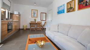 Eine moderne Küche mit Holdekor, ein Essbereich mit Tisch und Stühlen sowie ein Wohnzimmer mit einer Couch.