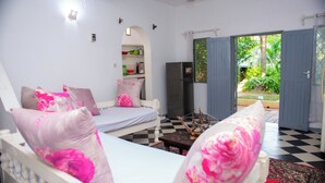A room with a bed, a sofa, a refrigerator, and a view of the outdoors. - Cosy beach villa (Malindi)