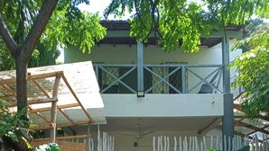 A two-story building with a covered patio area and a dirt pathway leading to the entrance. - Cosy beach villa (Malindi)