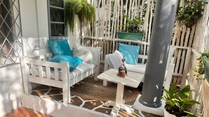 A patio area with white furniture, including a sofa and a table, surrounded by a white fence. There are potted plants and a small decorative item on the table. - Cosy beach villa (Malindi)