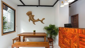 A modern reception area with a wooden reception desk, a large wall-mounted fish sculpture, and a large window overlooking a cityscape. - Comfy Corner Hotel (Chiang Mai)