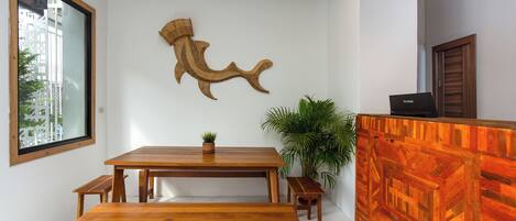 A modern reception area with a wooden reception desk, a large wall-mounted fish sculpture, and a large window overlooking a cityscape.