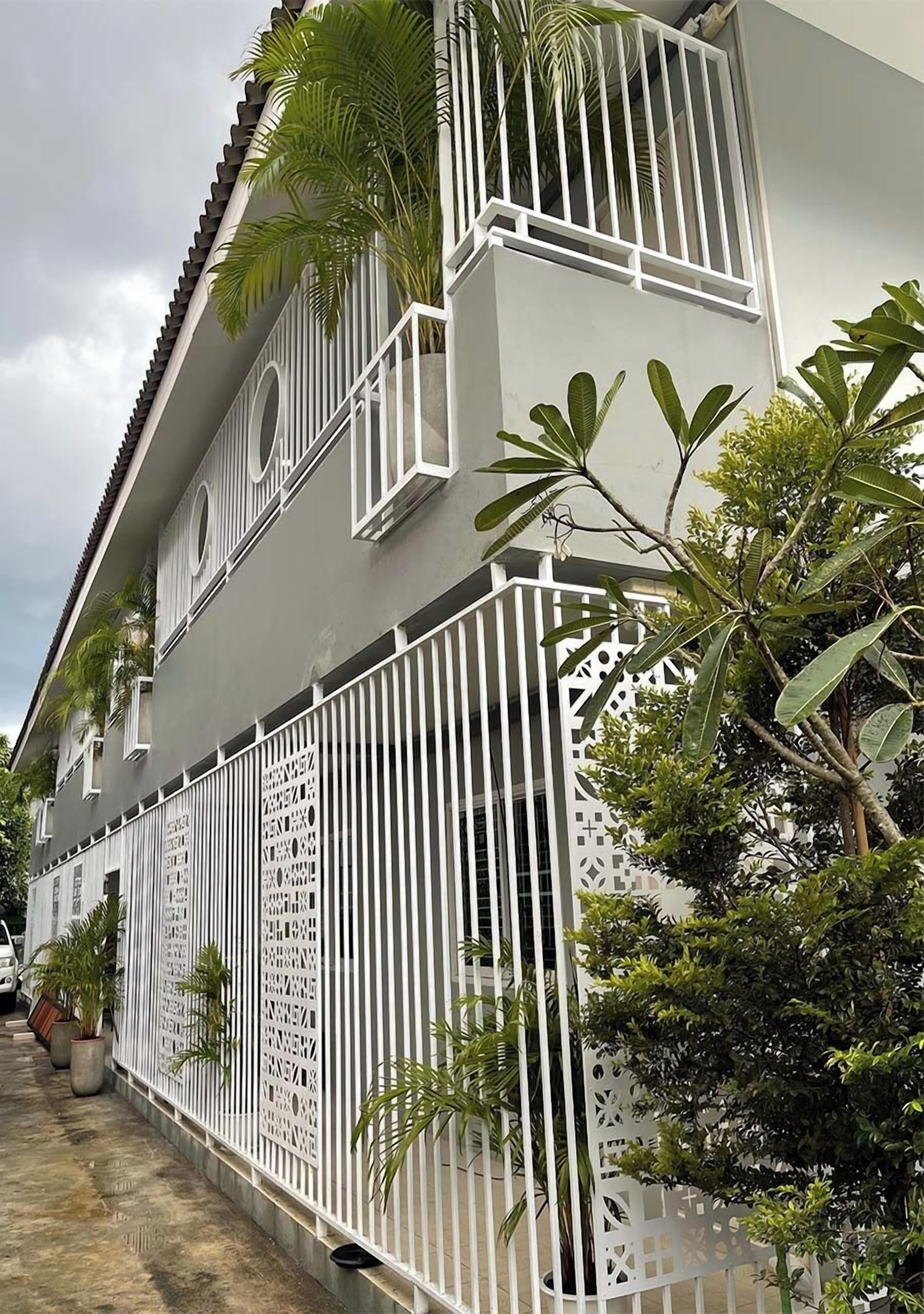 A modern building with a white exterior, multiple balconies, and a decorative white fence.