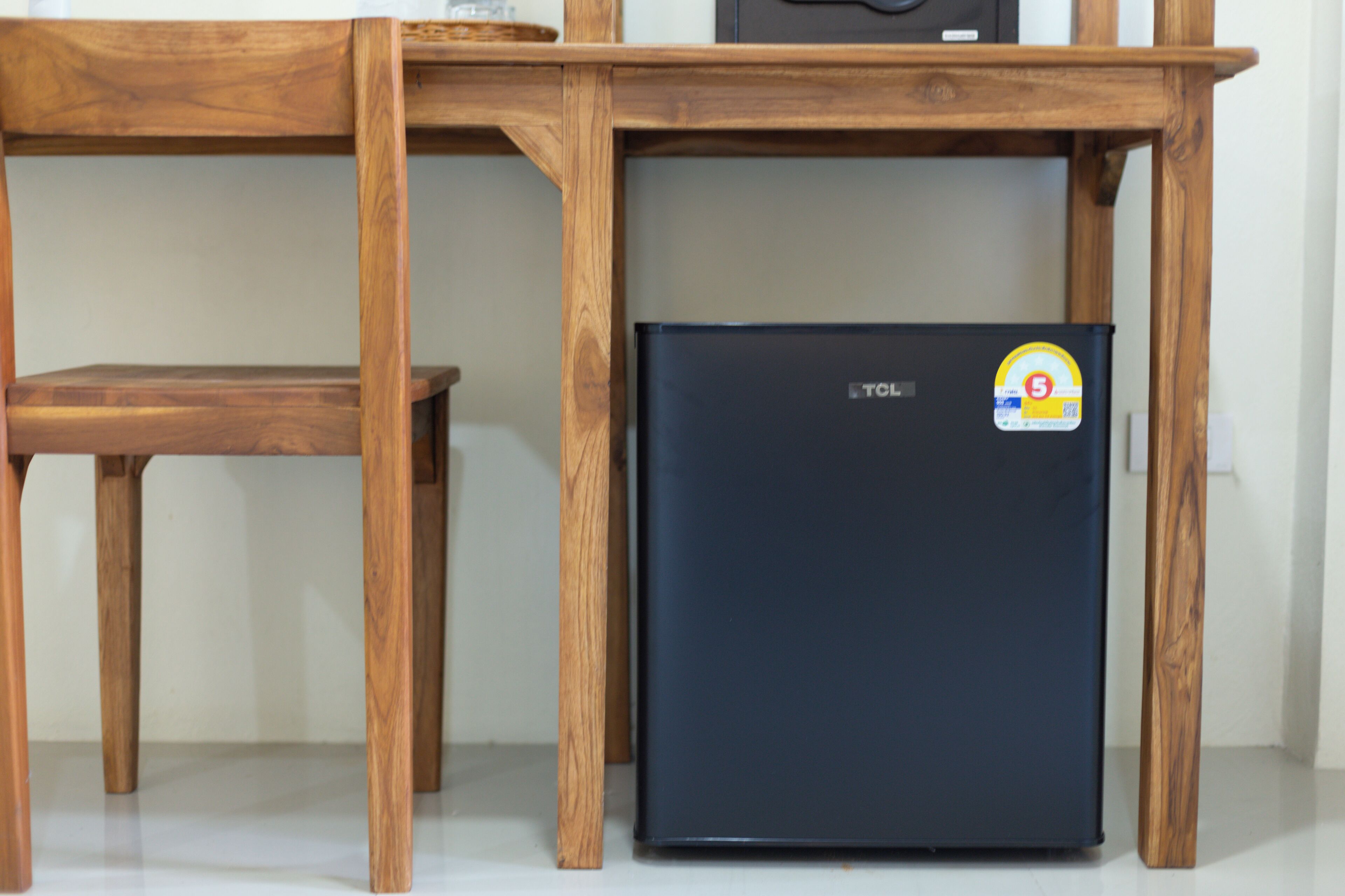 A wooden table with a black refrigerator underneath.