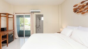 A bedroom with a bed, a wooden shelf, an air conditioning unit, and a shower area. - Comfy Corner Hotel (Chiang Mai)