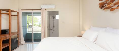 A bedroom with a bed, a wooden shelf, an air conditioning unit, and a shower area.