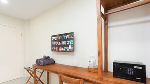 A room with a wooden table, a wall-mounted TV, a Kassa cash register, and a small wicker basket. - Comfy Corner Hotel (Chiang Mai)