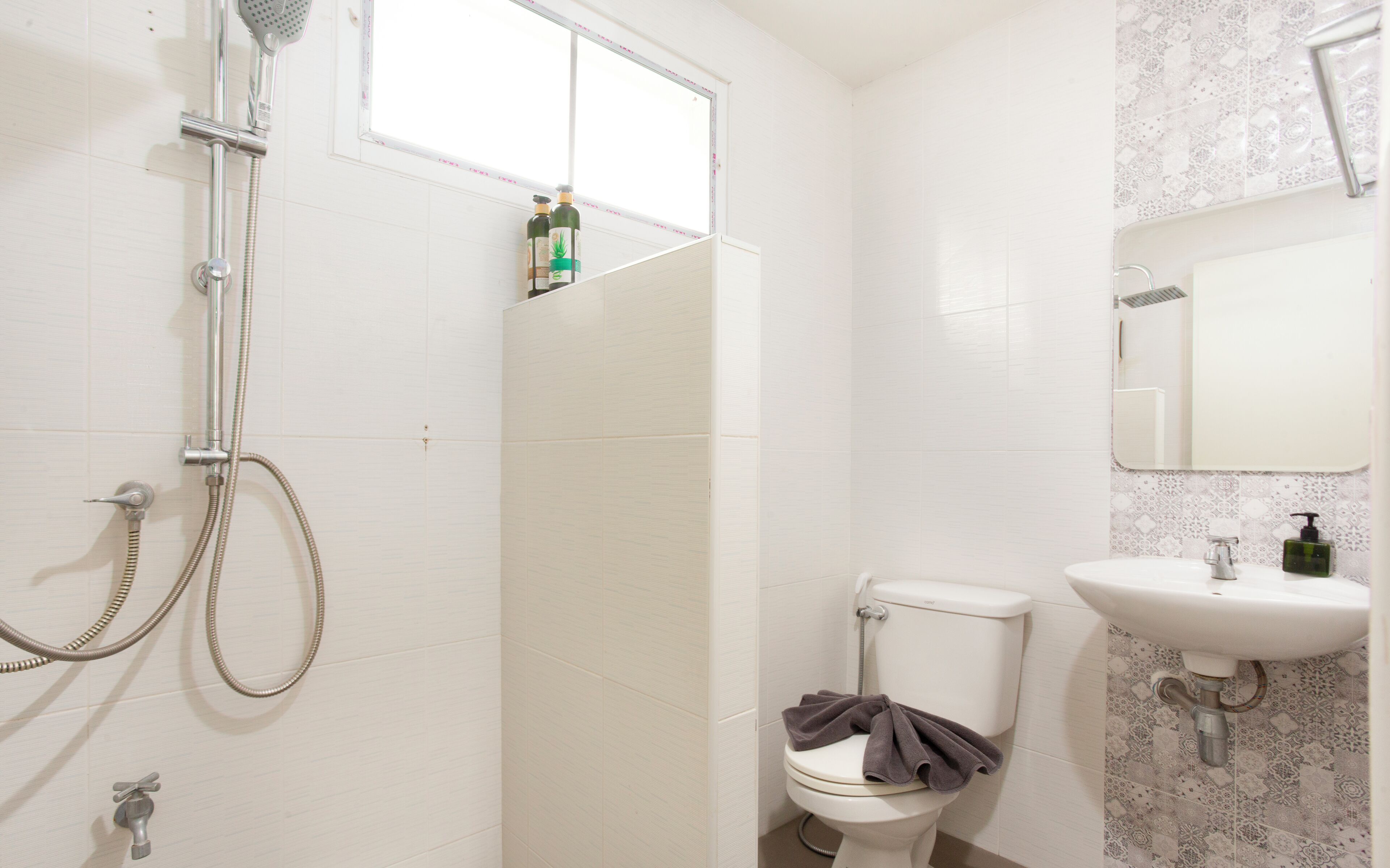 A bathroom with a shower, toilet, sink, and a window.