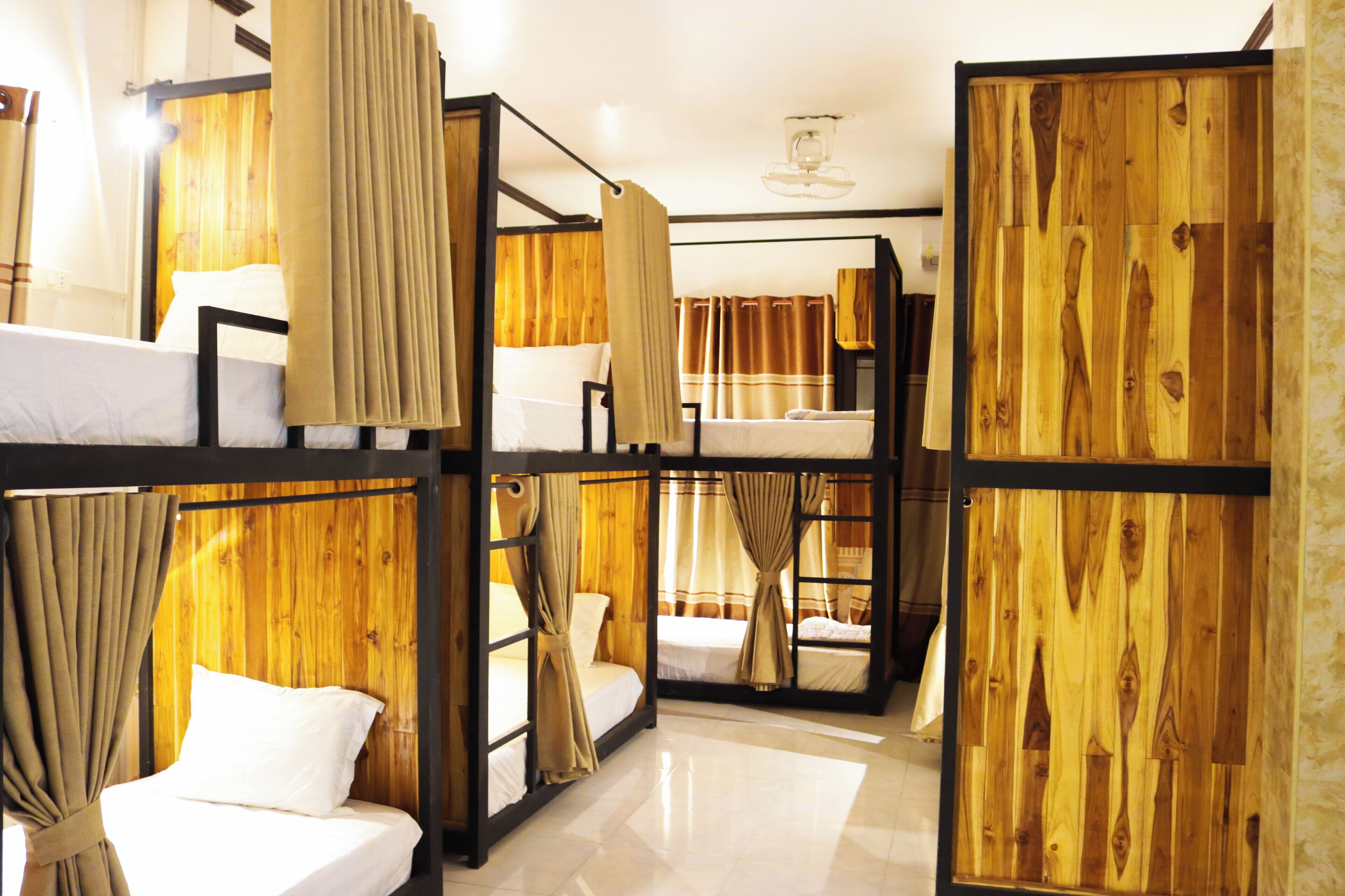 A hotel room with bunk beds, wooden paneling, and curtains.