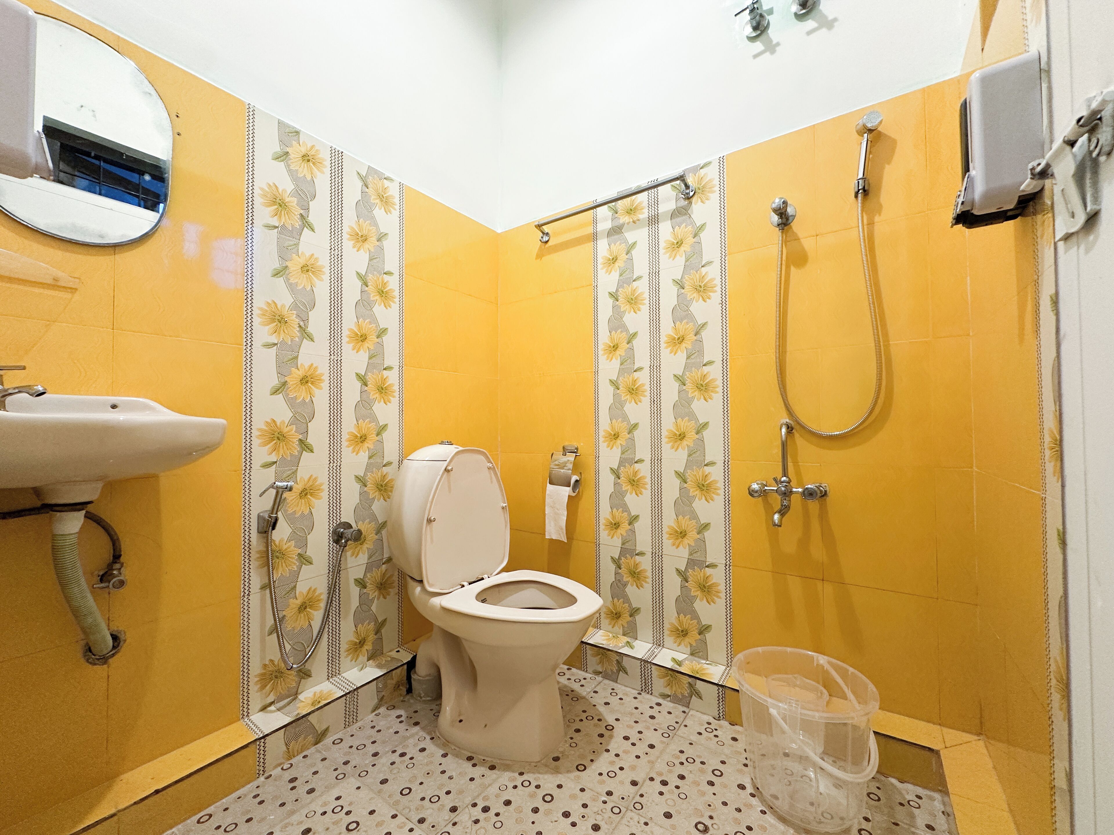 A bathroom with yellow walls, a toilet, a sink, and a shower.