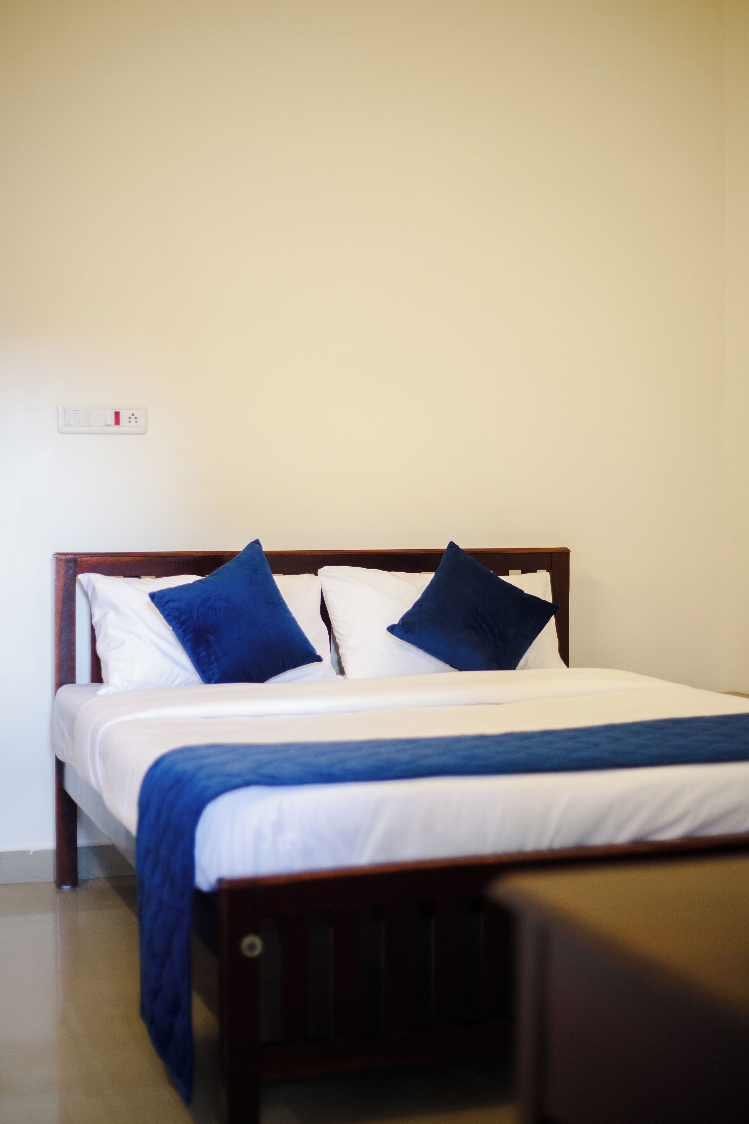 A bed with a wooden frame, white bedding, and blue pillows.