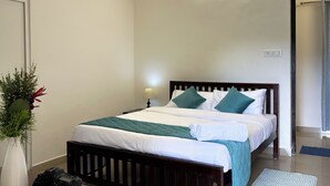 Ein Schlafzimmer mit einem Bett, einem Deckenventilator, einem Nachttisch mit Büchern und einem Beistelltisch.