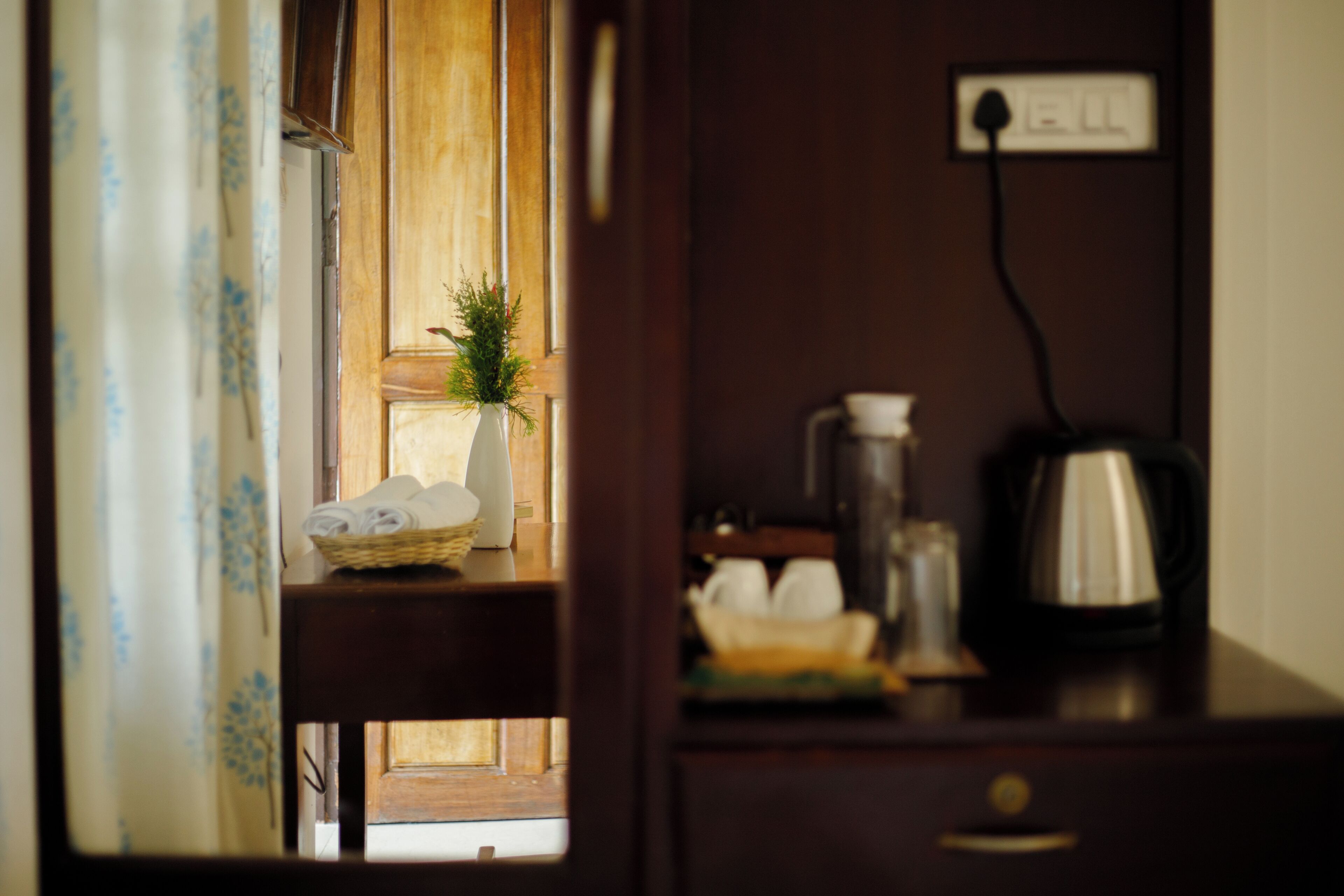 A wooden cabinet with a white vase and a basket of folded towels.