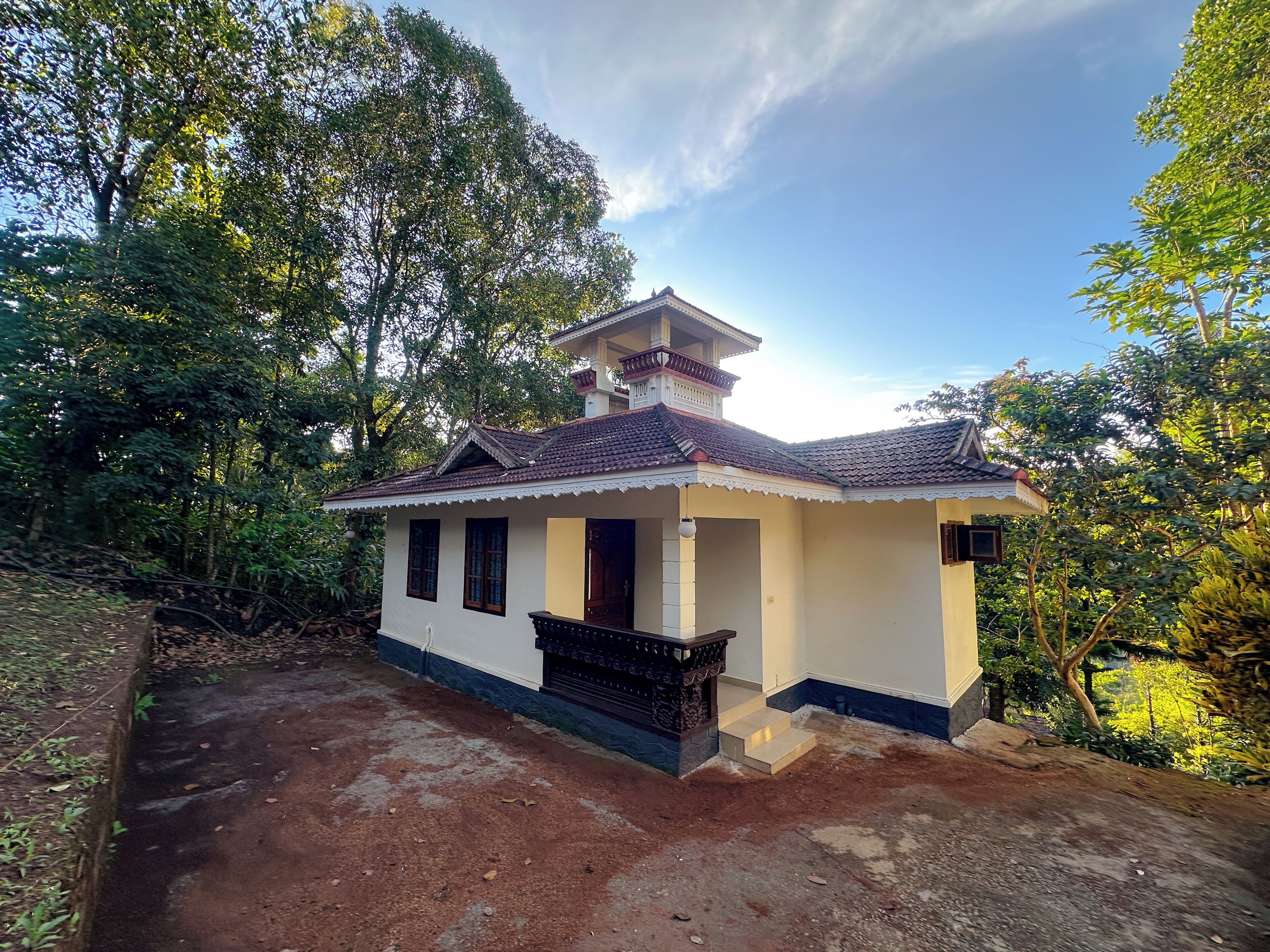 A small, single-story house with a tiled roof, a balcony, and a porch.