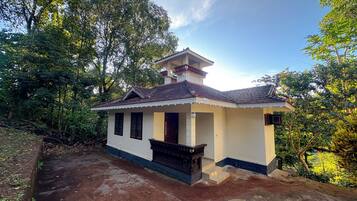 A small, single-story house with a tiled roof, a balcony, and a porch.