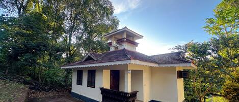 A small, single-story house with a tiled roof, a balcony, and a porch.