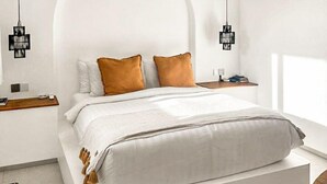 A modern bedroom with a large bed, two bedside tables, and a unique arched ceiling design. - Samastiti Bingin (Pecatu)