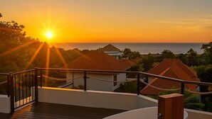A wooden deck with a large bathtub, overlooking a coastal area with houses and the sea during sunset. - Samastiti Bingin (Pecatu)