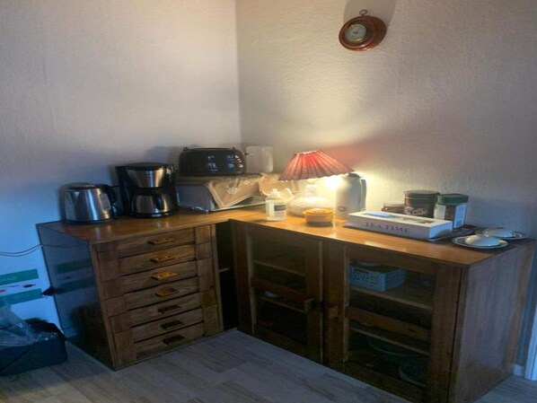 A compact kitchenette with a coffee maker, toaster, and tea timer on a wooden countertop.