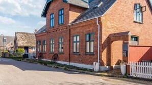 Ein Gebäude aus roten Ziegelsteinen mit einem steilen Satteldach und vielen Fenstern.