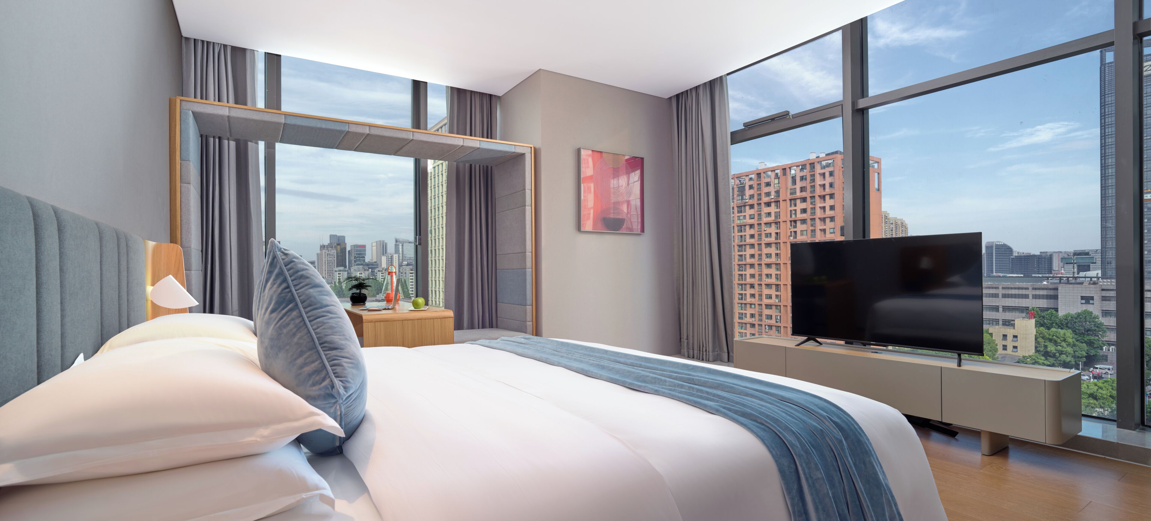 Une chambre d’hôtel moderne dotée d’un grand lit, d’une télévision et offrant une vue sur la ville.