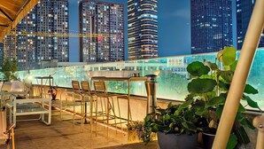 A rooftop terrace with outdoor seating, a view of city skyscrapers, and a glass barrier. - Pagoda Hotel Hangzhou Binjiang (Hangzhou)