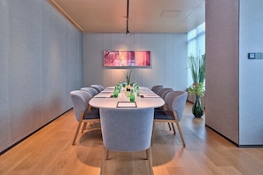 A conference room with a round table, grey chairs, a large abstract painting, and a potted plant. -  Pagoda Hotel Hangzhou Binjiang (Hangzhou)