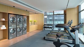 A modern hotel gym with multiple treadmills, a set of dumbbells, and a row of washing machines. - Pagoda Hotel Hangzhou Binjiang (Hangzhou)