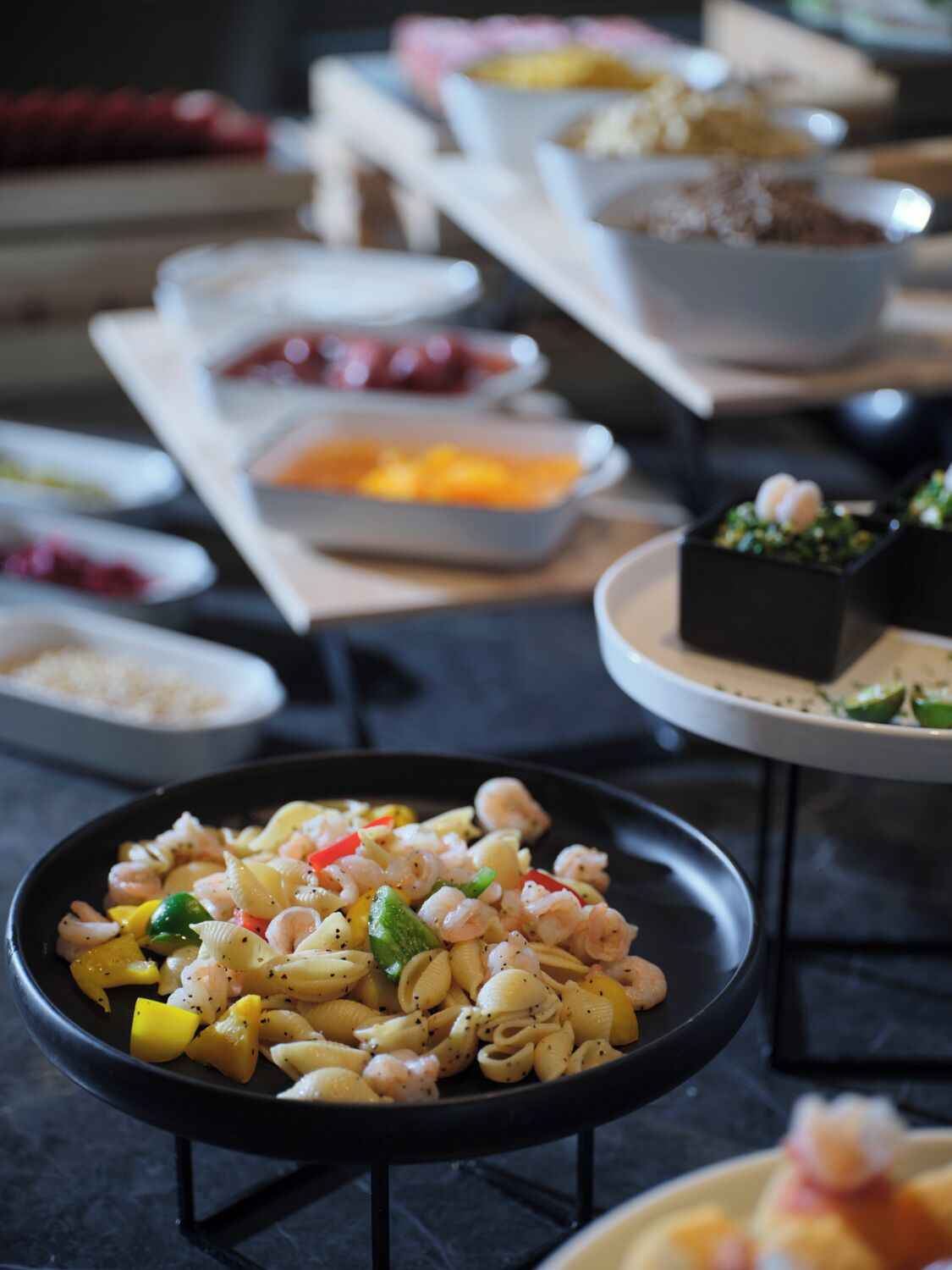 A buffet with various dishes, including pasta with shrimp and vegetables, and other food items in bowls and containers.